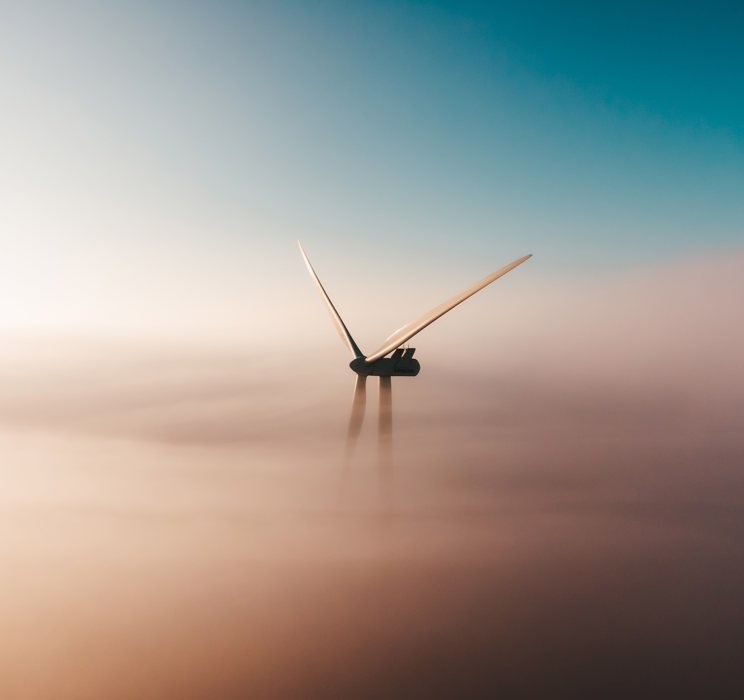 An image of a windmill in a misty environment with clear sky above. 